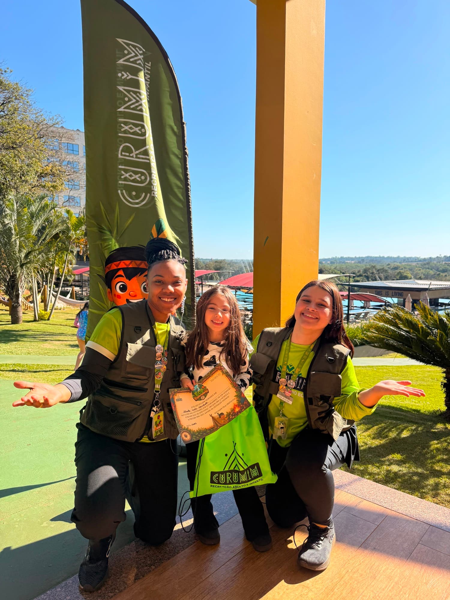 Equipe da recreação com criança segurando certificado, vista panorâmica do resort